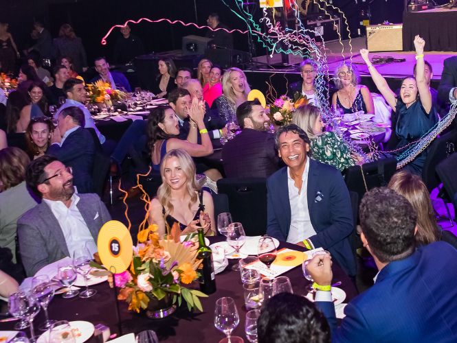 Increase your fundraising dollars with the best auctioneer, http://www.millphotostudio.com/ A joyful table of people with confetti in the air, enjoying their time thanks to the amazing auctioneer team at Astounding Auctions, Mill Photo Studio
